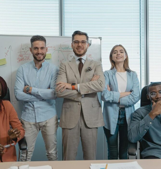 A multicultural group of business professionals confidently posing in a modern office.