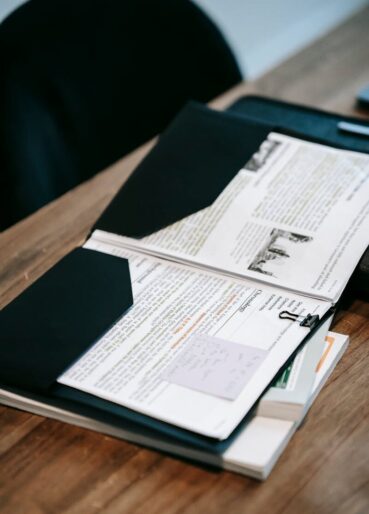 An open folder with papers and documents on a wooden desk representing educational or business material.