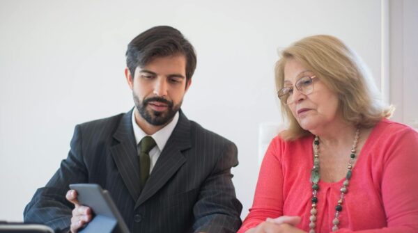 Business meeting in Portugal between a man and senior woman discussing with tablet.