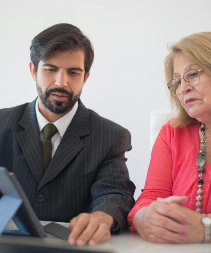 Business meeting in Portugal between a man and senior woman discussing with tablet.